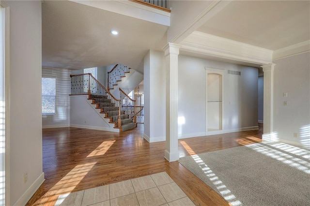 entryway featuring hardwood / wood-style flooring, decorative columns, and crown molding