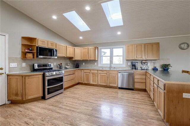 kitchen with appliances with stainless steel finishes, lofted ceiling, light hardwood / wood-style flooring, and light brown cabinetry