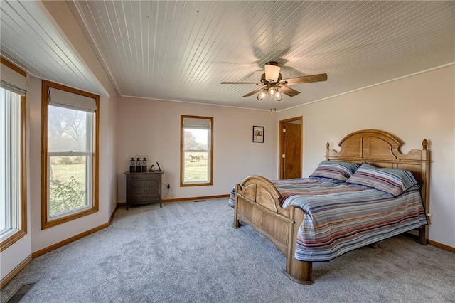 carpeted bedroom with multiple windows, ceiling fan, crown molding, and wood ceiling