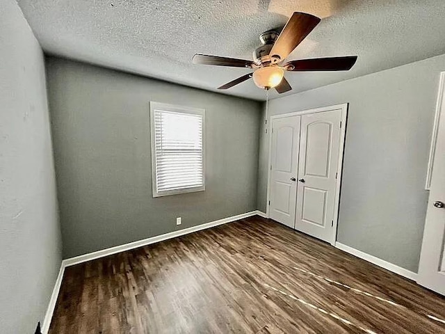 unfurnished bedroom with a textured ceiling, ceiling fan, a closet, and dark hardwood / wood-style floors