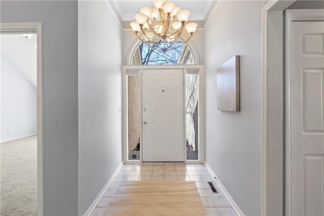 entryway featuring light carpet, a towering ceiling, ornamental molding, and an inviting chandelier