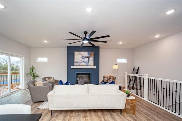 living room with a fireplace, light hardwood / wood-style floors, and ceiling fan