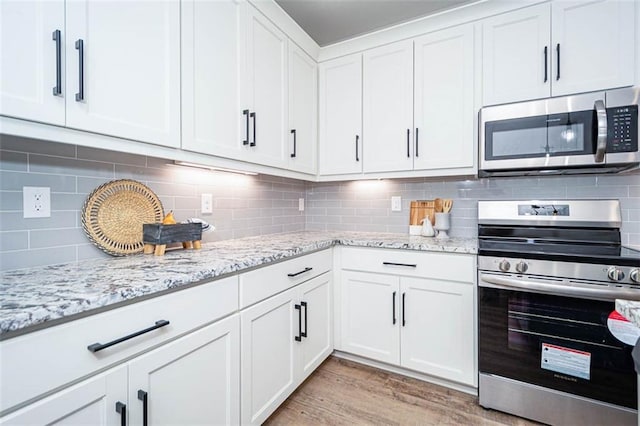 kitchen featuring stainless steel appliances, white cabinetry, and decorative backsplash