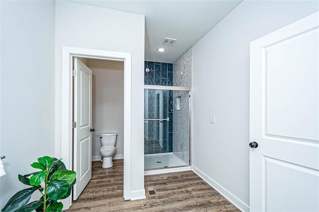 bathroom featuring hardwood / wood-style flooring, an enclosed shower, and toilet