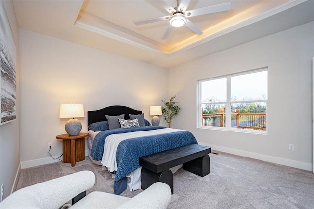 bedroom with ceiling fan, a tray ceiling, and light colored carpet