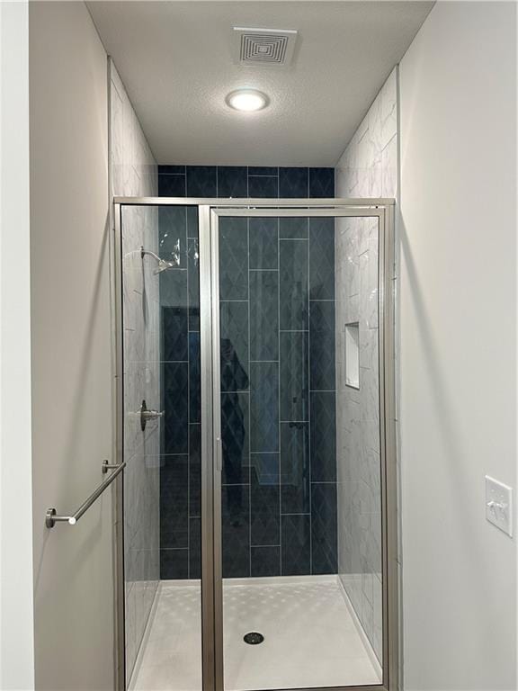 bathroom with a textured ceiling and walk in shower