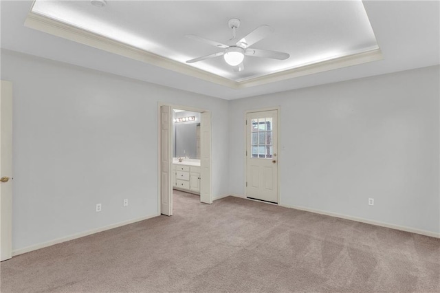 spare room with ceiling fan, light colored carpet, ornamental molding, and a tray ceiling