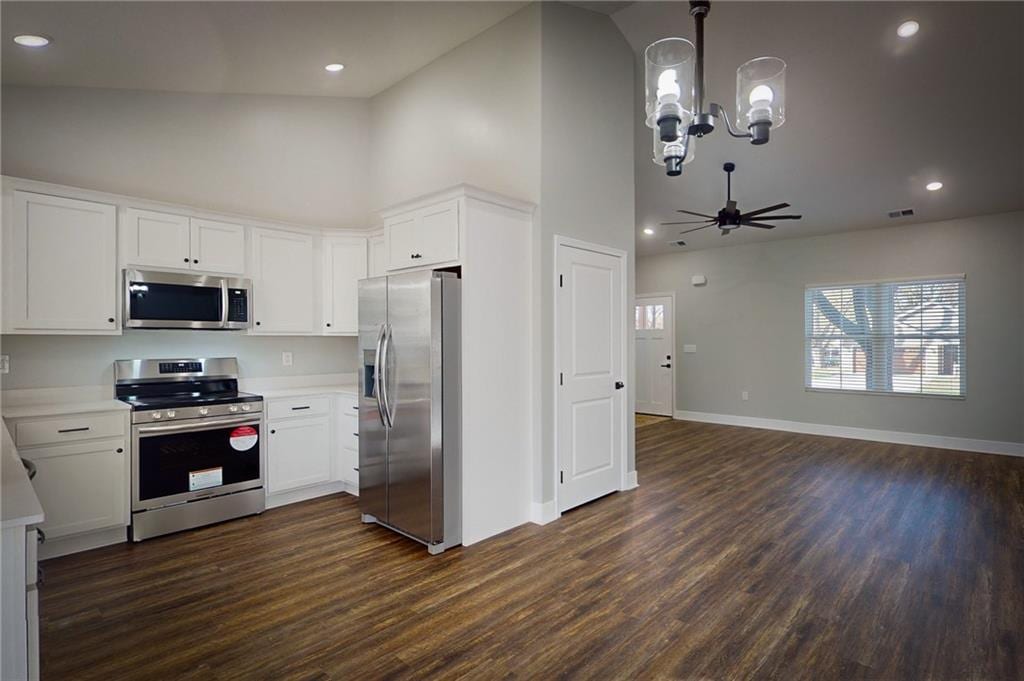 kitchen with white cabinets, dark hardwood / wood-style flooring, stainless steel appliances, and ceiling fan with notable chandelier