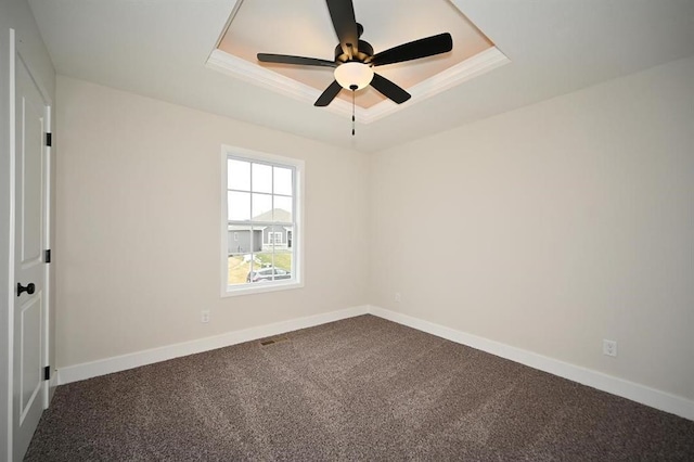 spare room with a raised ceiling, ornamental molding, carpet, and ceiling fan