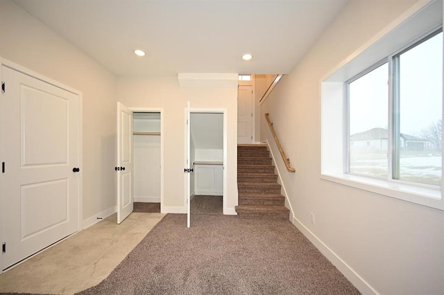 interior space featuring multiple windows, light carpet, and a closet