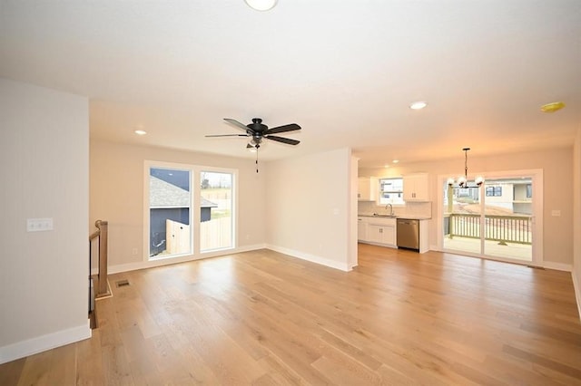 unfurnished living room featuring ceiling fan with notable chandelier, sink, and light hardwood / wood-style flooring