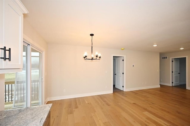 unfurnished room with an inviting chandelier and light hardwood / wood-style floors