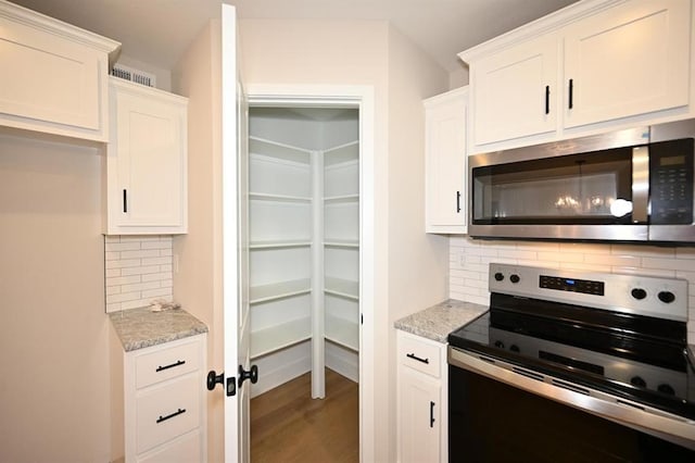 kitchen featuring stainless steel appliances, hardwood / wood-style flooring, white cabinets, and light stone counters