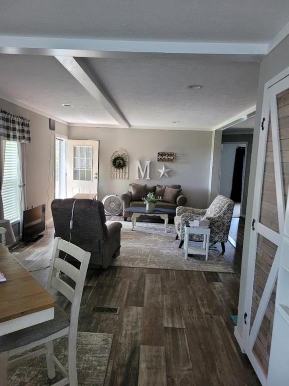 living room with hardwood / wood-style floors, beam ceiling, and a textured ceiling