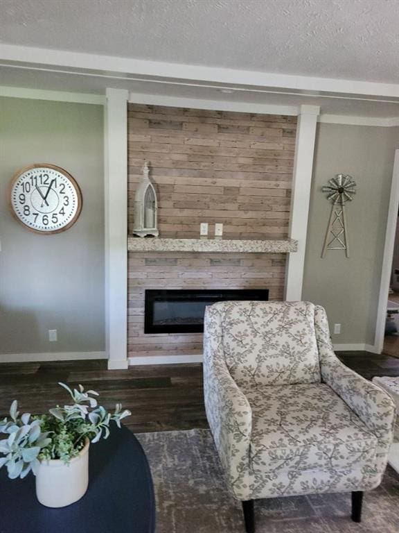 living area with wooden walls, a fireplace, dark hardwood / wood-style floors, and a textured ceiling