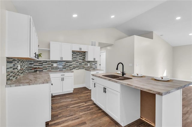 kitchen with sink, dark hardwood / wood-style floors, an island with sink, white cabinets, and vaulted ceiling