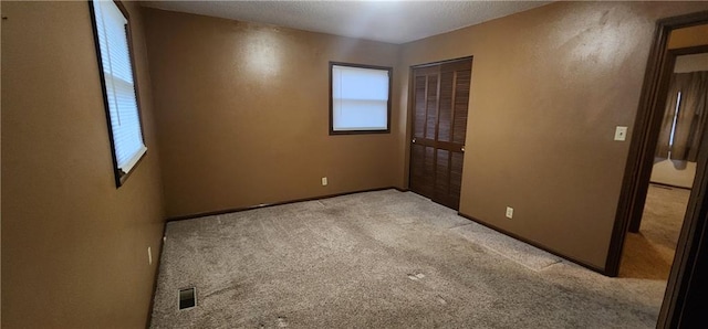 unfurnished bedroom featuring multiple windows, light carpet, and a closet