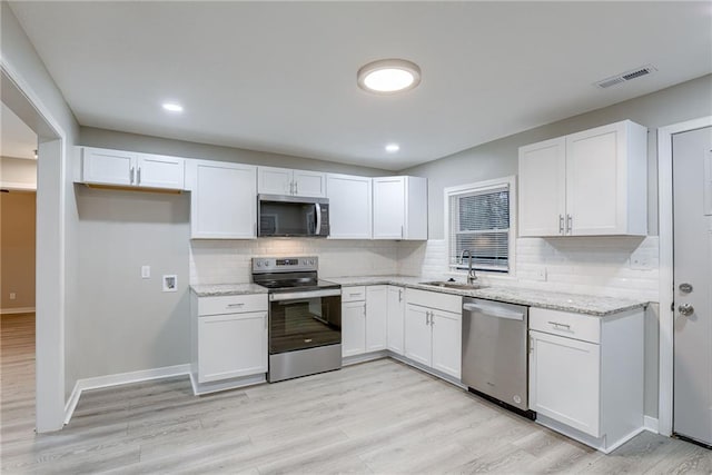 kitchen with tasteful backsplash, white cabinetry, sink, and stainless steel appliances