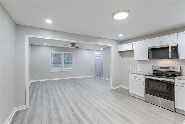 kitchen with white cabinets, light stone counters, light wood-type flooring, and appliances with stainless steel finishes