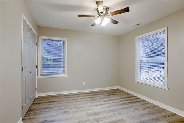 spare room featuring ceiling fan, a healthy amount of sunlight, and light hardwood / wood-style floors