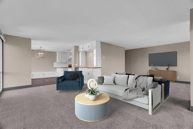 living room featuring carpet floors, baseboards, and a notable chandelier