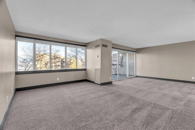 carpeted spare room with visible vents and baseboards