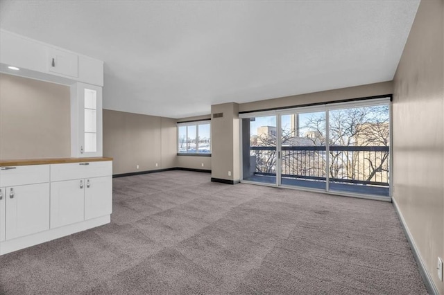 unfurnished living room with carpet floors and baseboards