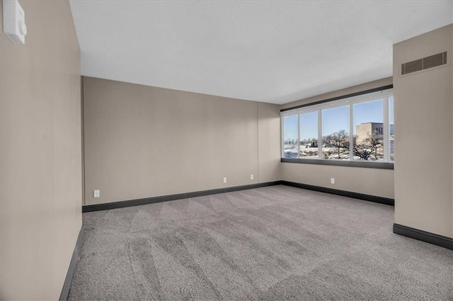 carpeted spare room featuring visible vents and baseboards