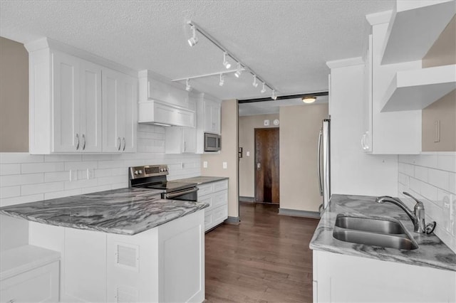 kitchen featuring a peninsula, dark wood-type flooring, a sink, white cabinets, and appliances with stainless steel finishes