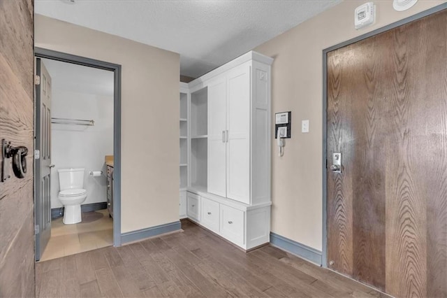 interior space featuring a textured ceiling, baseboards, and wood finished floors