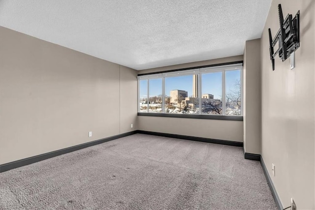 empty room with a city view, carpet flooring, a textured ceiling, and baseboards