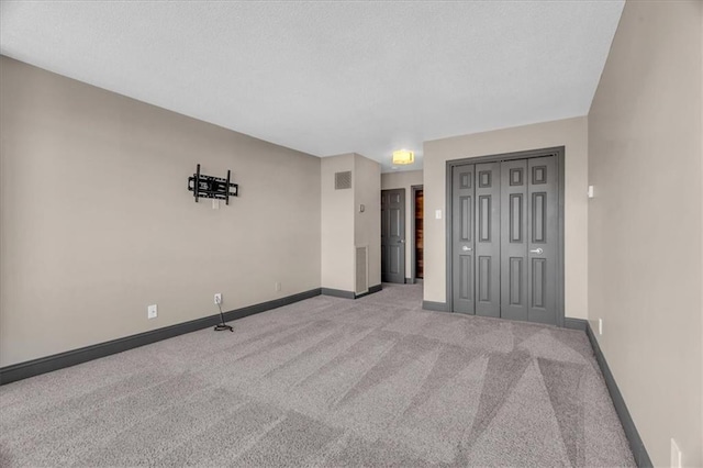 carpeted empty room featuring visible vents, baseboards, and a textured ceiling