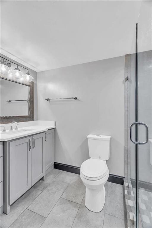 bathroom with a stall shower, baseboards, vanity, and toilet