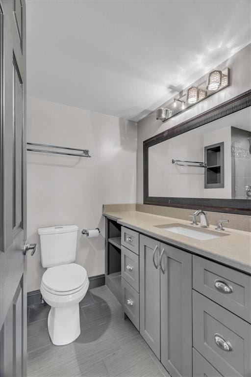 bathroom featuring toilet, baseboards, and vanity