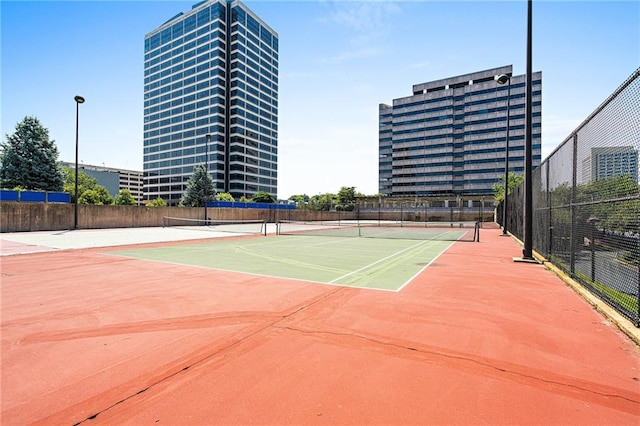 view of tennis court with community basketball court and fence