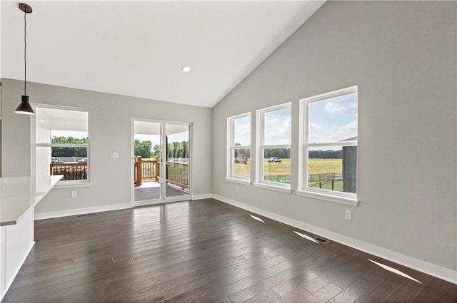 unfurnished living room featuring plenty of natural light, dark hardwood / wood-style flooring, and high vaulted ceiling