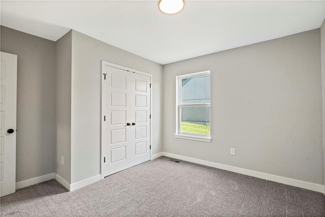 unfurnished bedroom with light colored carpet and a closet