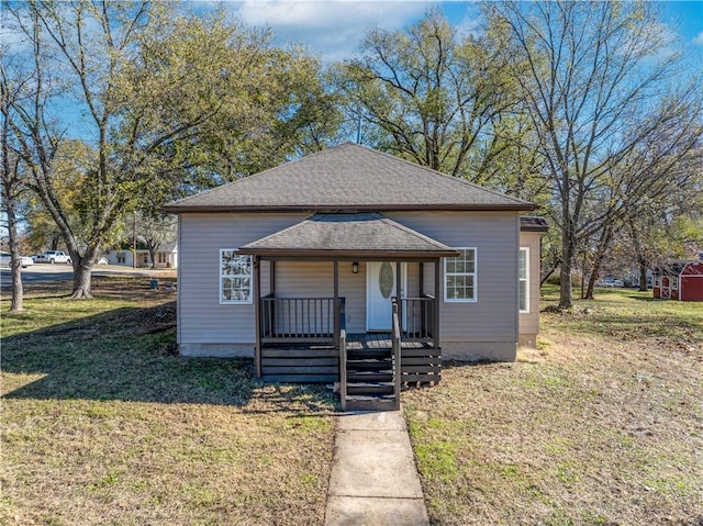 bungalow featuring covered porch and a front yard