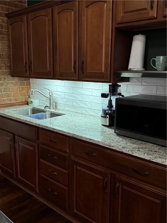 kitchen with decorative backsplash, light stone counters, sink, and dark hardwood / wood-style floors