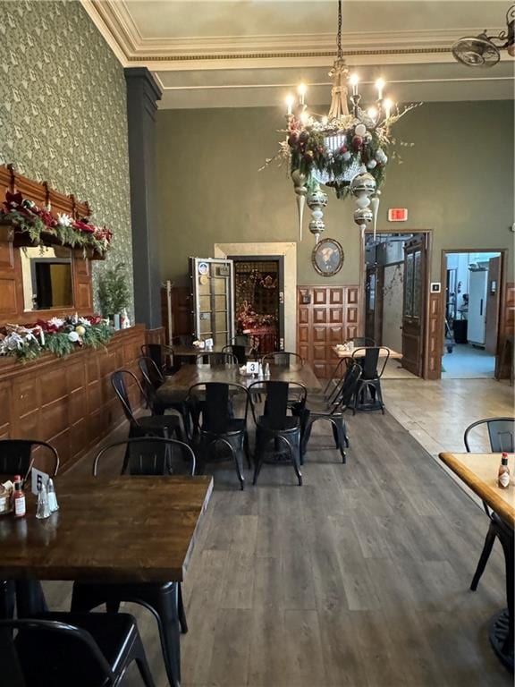 dining area with a chandelier, hardwood / wood-style floors, a towering ceiling, and crown molding