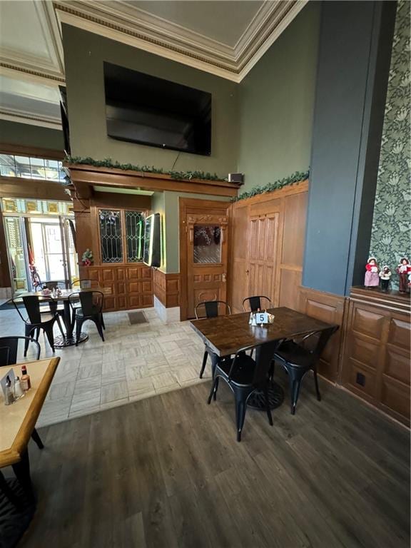 dining area with hardwood / wood-style floors, ornamental molding, and a towering ceiling