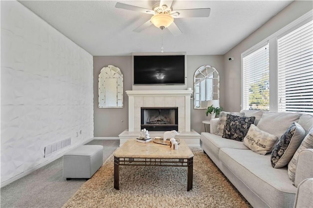 living room with ceiling fan, carpet floors, and a tiled fireplace