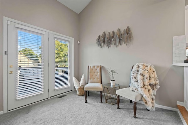 sitting room with carpet floors and vaulted ceiling