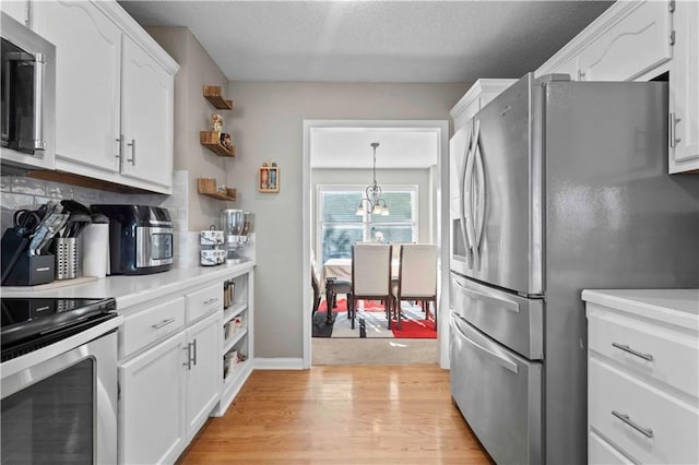 kitchen featuring stainless steel appliances, an inviting chandelier, white cabinets, light hardwood / wood-style floors, and hanging light fixtures