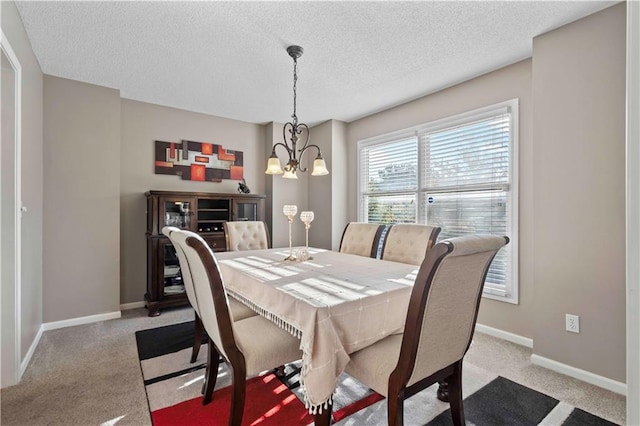 carpeted dining room featuring a chandelier and a textured ceiling