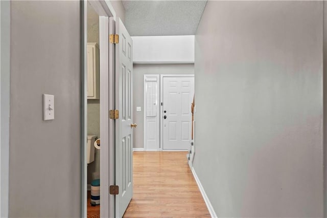 corridor featuring light wood-type flooring and a textured ceiling