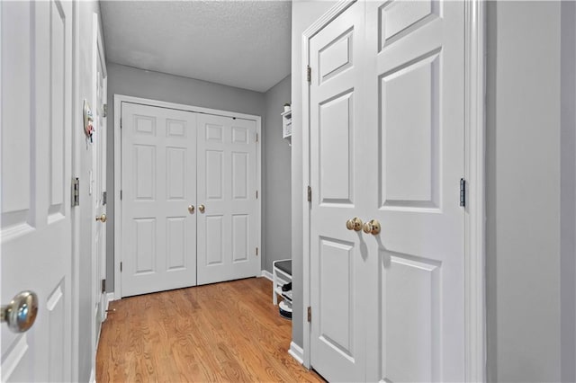 hall featuring a textured ceiling and light wood-type flooring