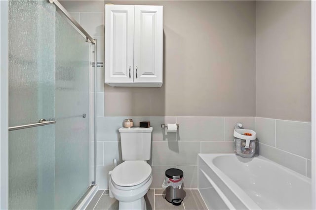 bathroom featuring plus walk in shower, tile walls, and toilet