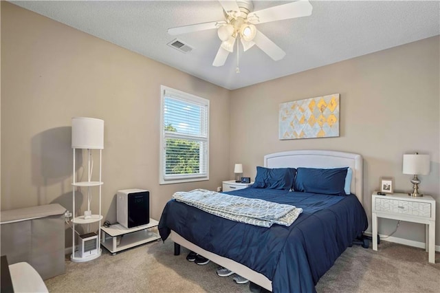 carpeted bedroom featuring ceiling fan and a textured ceiling