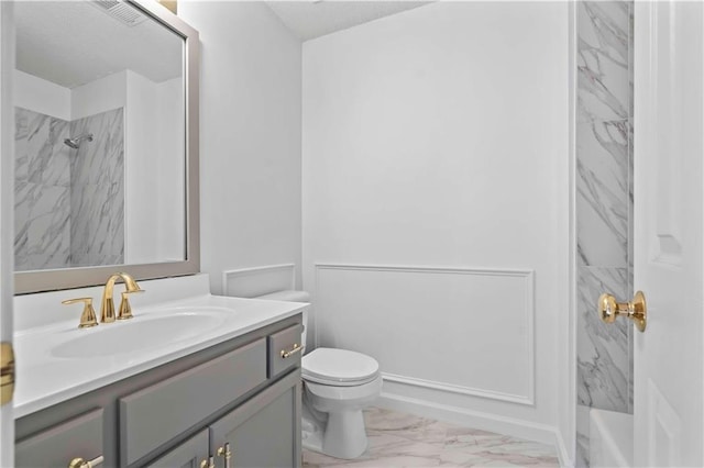 bathroom with tiled shower, vanity, and toilet